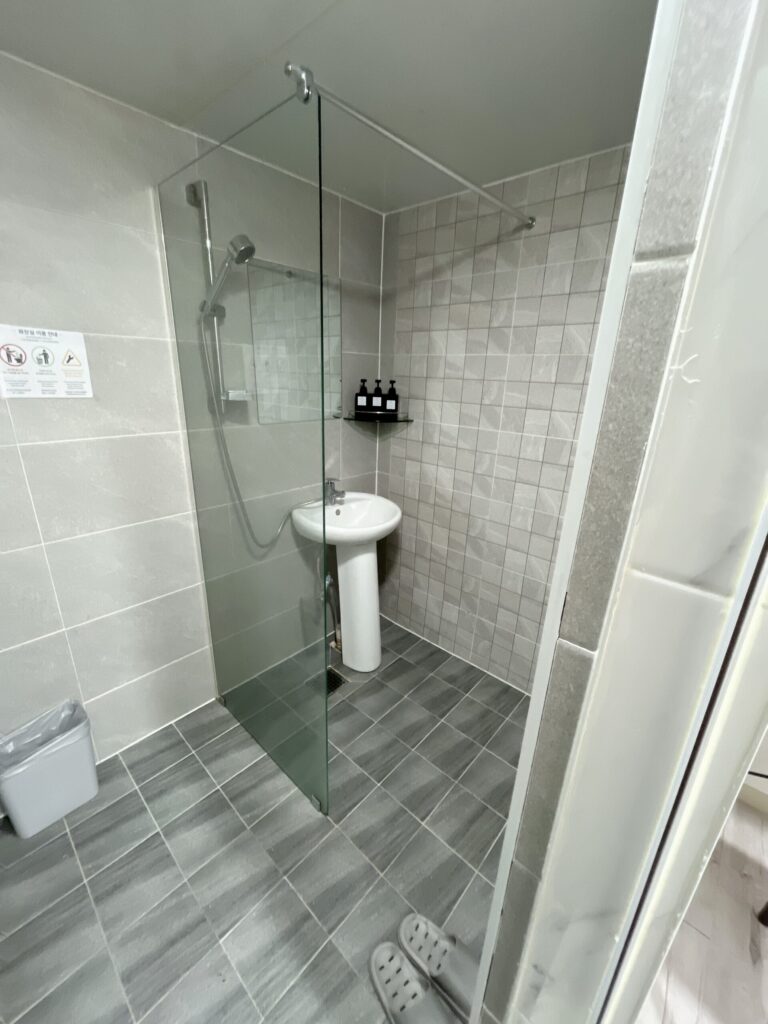 「Jongno KS Stay」ゲストハウスシャワーエリアとトイレの間には水はねを防ぐ仕切りパネルが設置されています